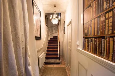 a hallway with a staircase with a chandelier at Maison 1888 Carcassonne - Roof Terrace & Cité Views in Carcassonne