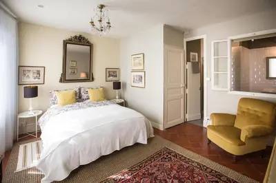 a bedroom with a bed and a chair and a mirror at Maison 1888 Carcassonne - Roof Terrace & Cité Views in Carcassonne
