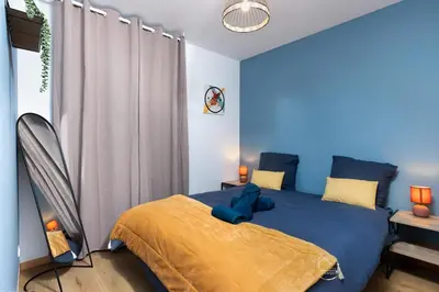 a bedroom with a blue bed with a yellow blanket at L'écrin Carcassonnais- parking gratuit- Terrasse in Carcassonne
