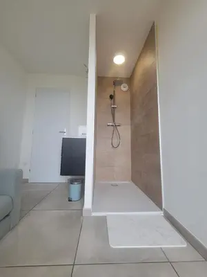 a bathroom with a shower with a television in it at L'Escale du Puits in Puylaurens