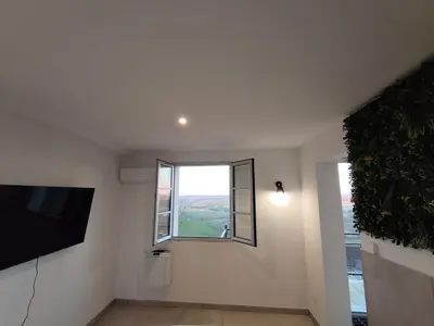 a living room with a flat screen tv and a window at L'Escale du Puits in Puylaurens