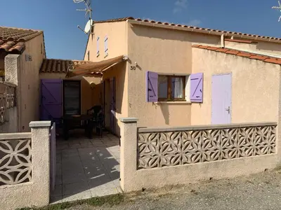 a house with purple doors and a fence at AIG 56 – Pavillon T3 – Résidence Les Jardins d’Erato – Gruissan – 5 personnes in Gruissan