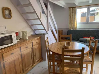a living room with a table and a kitchen with a microwave at AIG 56 – Pavillon T3 – Résidence Les Jardins d’Erato – Gruissan – 5 personnes in Gruissan