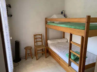 a room with two bunk beds and a chair at AIG 56 – Pavillon T3 – Résidence Les Jardins d’Erato – Gruissan – 5 personnes in Gruissan