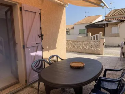 a table and chairs on a patio with a door at AIG 56 – Pavillon T3 – Résidence Les Jardins d’Erato – Gruissan – 5 personnes in Gruissan