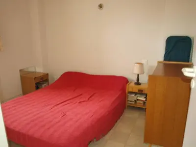 a bedroom with a red bed and a blue chair at AIG 56 – Pavillon T3 – Résidence Les Jardins d’Erato – Gruissan – 5 personnes in Gruissan