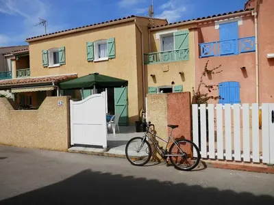 a bike parked in front of a house with a white fence at Villa confortable, parking, animaux OK - 6 pers. - FR-1-796-109 in Gruissan