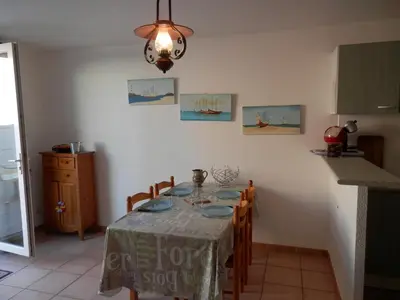 a dining room with a table and a kitchen at Villa confortable, parking, animaux OK - 6 pers. - FR-1-796-109 in Gruissan