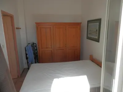 a bedroom with a bed and a wooden cabinet at Villa confortable, parking, animaux OK - 6 pers. - FR-1-796-109 in Gruissan