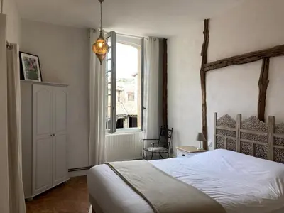 a bedroom with a white bed and a window at Gîte de l'oiseau bleu in Lautrec