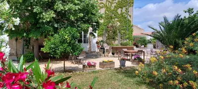 a garden with a table and chairs and flowers at Maison Matisse in Saint-Nazaire-dʼAude