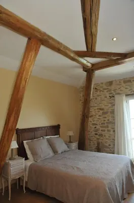 a bedroom with a large bed with wooden beams at Maison Matisse in Saint-Nazaire-dʼAude