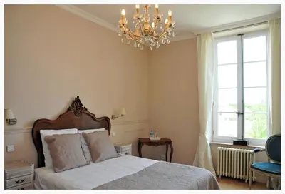 a bedroom with a bed and a chandelier at Maison Matisse in Saint-Nazaire-dʼAude