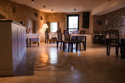 a dining room with tables and chairs and a kitchen at Le Relais De Pigasse in Ouveillan