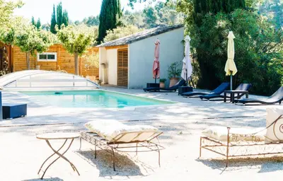 a swimming pool with chairs and umbrellas next to a house at Le Relais De Pigasse in Ouveillan