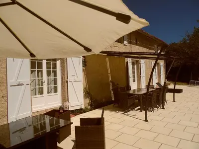 a patio with an umbrella and a table and chairs at Gîte Belfloret in Renneville