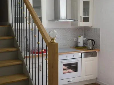 a kitchen with white cabinets and a staircase at Gîte Belfloret in Renneville