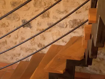 a set of wooden stairs in front of a stone wall at Sunny Escape to Serenity in Fraissé-des-Corbières