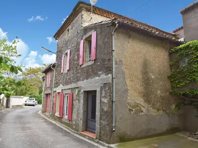 an old building with pink shutters on a street at Village House in La Caunette with Pool in La Caunette