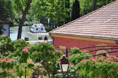 a boat in the water with a house and flowers at Vinauberge in Poilhès