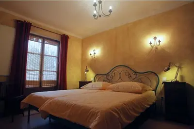 a bedroom with a large bed with white sheets and a window at Vinauberge in Poilhès