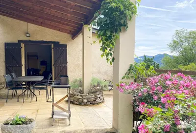 a patio with a table and chairs and flowers at Gite de Serrelongue in Montségur