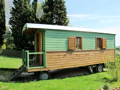 a green tiny house sitting in a field at Les Roulottes Du Lauragais in Montmaur