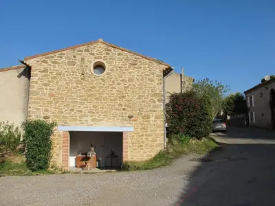 a brick building with a garage with a table in it at Les Roulottes Du Lauragais in Montmaur