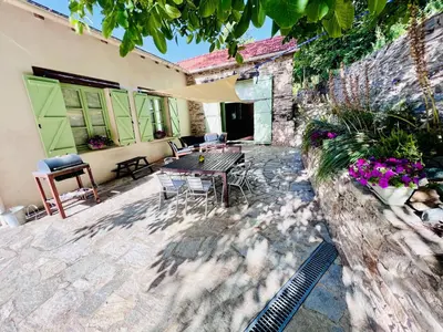 a patio with a table and chairs and a building at Les Coumayres in Riols