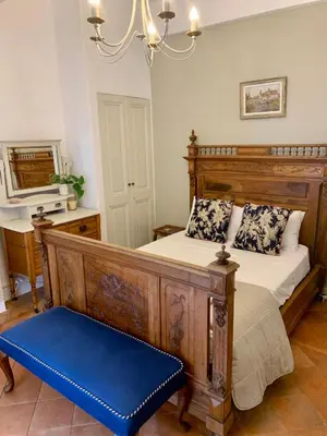 a bedroom with a wooden bed and a blue bench at L'Ancienne Boulangerie in Caunes-Minervois