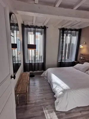 a bedroom with a bed and a table and windows at La Caponnière in Carcassonne