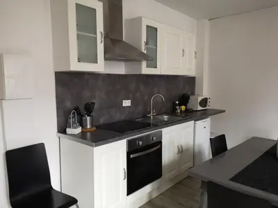 a kitchen with white cabinets and a sink at Appartement du GET in Revel