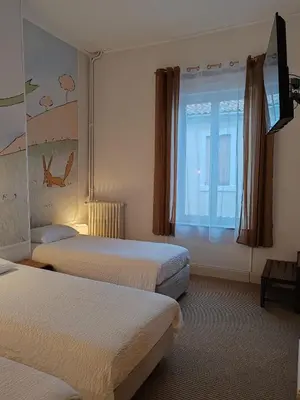 a hotel room with two beds and a window at Hotel de France in Narbonne