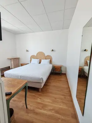 a bedroom with a bed and a wooden floor at Hotel de France in Narbonne