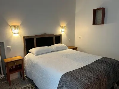 a bedroom with a bed and two lights on the wall at Hotel de France in Narbonne