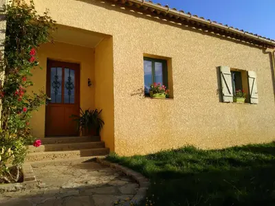 a house with two windows and a door with flowers at La Claouzo in Duilhac