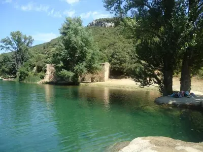 a body of water with trees and a mountain at La Claouzo in Duilhac