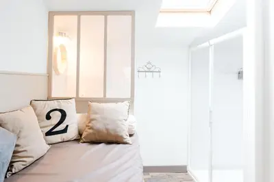a white room with a couch with two pillows at La Maison Gustave in Narbonne