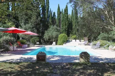 a swimming pool with a red umbrella and trees at Château d'Agel gite in Agel