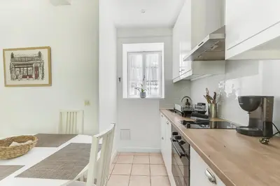 a kitchen with white walls and a table and a counter at Bellevue Cité Chez Jean - vue directe Cité, Cité à 200m, clim, parking public gratuit à 200m, WIFI - Direct view Cité, 200m to Cité, Aircon, free public car park 200m, WIFI in Carcassonne