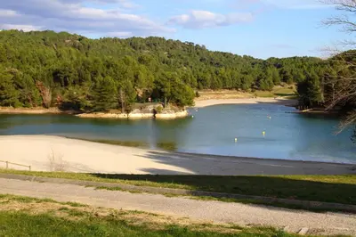 a body of water with a beach and trees at Bellevue Cité Chez Jean - vue directe Cité, Cité à 200m, clim, parking public gratuit à 200m, WIFI - Direct view Cité, 200m to Cité, Aircon, free public car park 200m, WIFI in Carcassonne