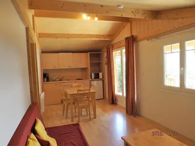 a living room with a table and a kitchen at Les chalets du Relais d'Aguilar in Tuchan
