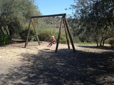 a little girl is playing on a swing at Les chalets du Relais d'Aguilar in Tuchan