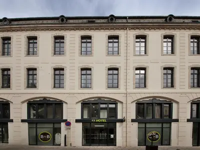 a large brick building with windows and a store at B&B HOTEL Castres Centre Gambetta in Castres