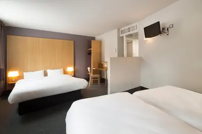 a hotel room with two beds and a desk at B&B HOTEL Castres Centre Gambetta in Castres