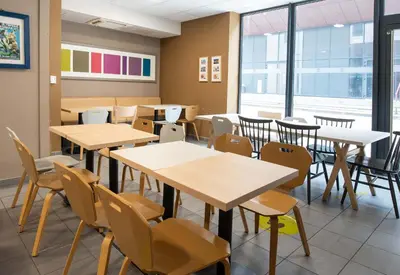 a classroom with tables and chairs and windows at B&B HOTEL Castres Centre Gambetta in Castres