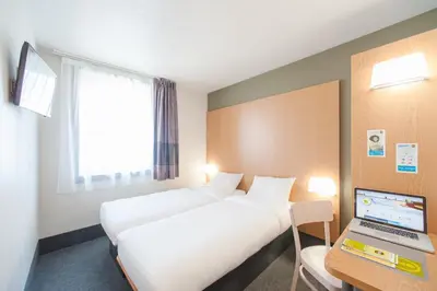 a hotel room with two beds and a laptop on a desk at B&B HOTEL Castres Centre Gambetta in Castres