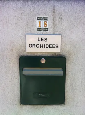a green mailbox with a sign on top of it at Les Orchidées in Carcassonne