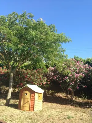 a dog house sitting in the grass next to a tree at Les Orchidées in Carcassonne