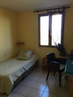 a bedroom with a bed and a chair and a window at Les Orchidées in Carcassonne